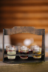 Multicolored alcoholic tinctures in 30 milliliter glasses on a wooden stand. Transcarpathian culture Ukraine