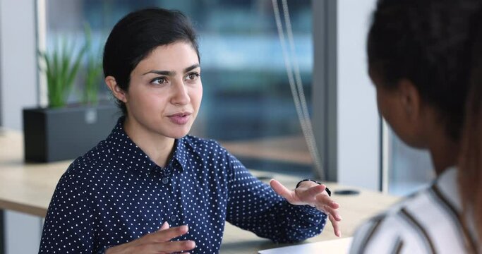 Close up Indian businesswoman talks to company client, colleague or apprentice, consulting, share opinion and thoughts, work on project, engaged in teamwork, sell services, give professional advice