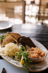 Salmon tartare served with grated butter and roasted bread. Table with food on terrace