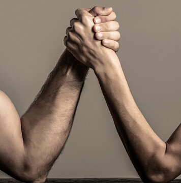 Two man's hands clasped arm wrestling, strong and weak, unequal match. Arm wrestling thin hand and a big strong arm in studio