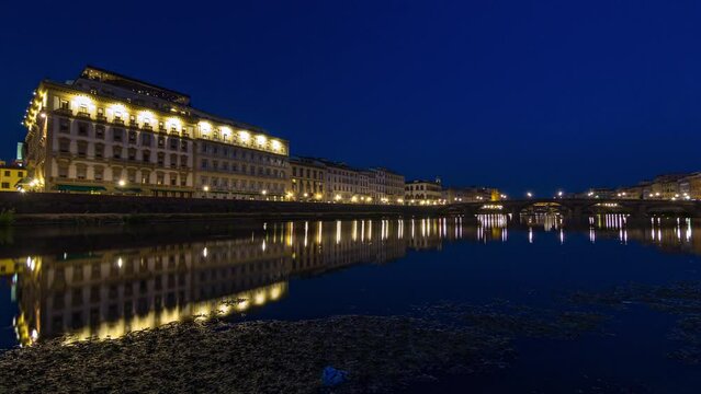 Twilight scene of Ponte Alla Carraia and and illuminated historical buildings day to night transition timelapse over River Arno with reflections on water after sunset. Florence, Tuscany, Italy