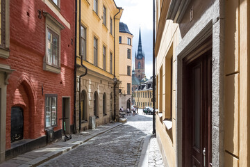 View of Riddarholmen Church, former medieval Greyfriars Monastery and final resting place of most Swedish monarchs, from the narrow streets of Gamla Stan, medieval city center of Stockholm, Sweden