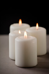 Fototapeta na wymiar set of burning white candles on the shelf with black background