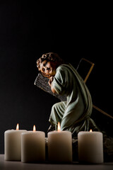 statue of christian jesus child with candles, black background