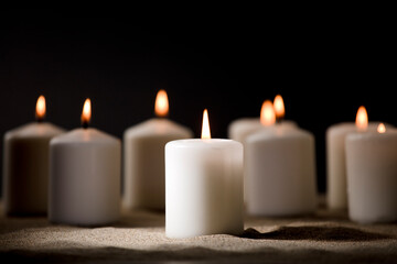 bullying concept, composed by group of lit candles, on sand with black night background