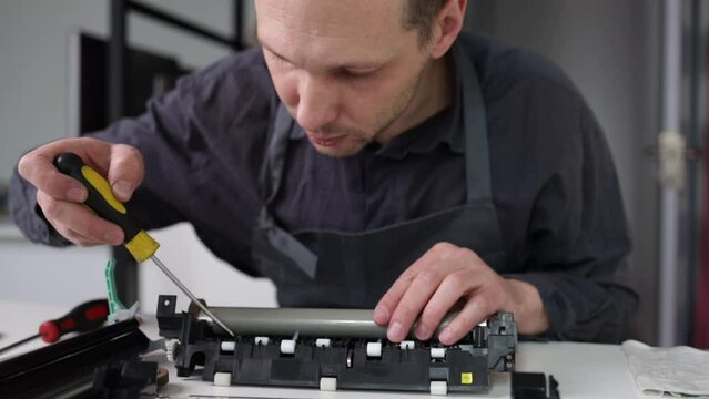 printer repair technician. A male handyman repairs a printer in a client's apartment. Fuser part