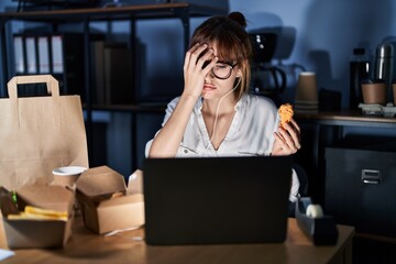 Young beautiful woman working using computer laptop and eating delivery food yawning tired covering half face, eye and mouth with hand. face hurts in pain.