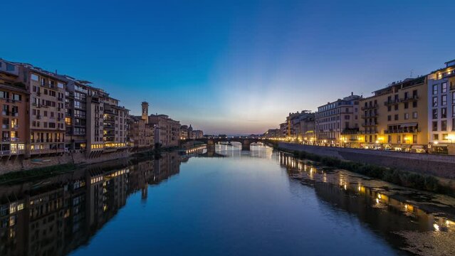 Twilight scene of Ponte Santa Trinita (Holy Trinity Bridge) day to night transition panoramic timelapse over River Arno with reflections on water after sunset, old houses on the side. Florence, Italy