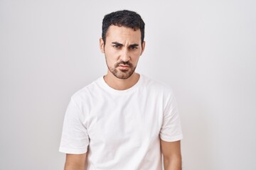 Handsome hispanic man standing over white background skeptic and nervous, frowning upset because of problem. negative person.