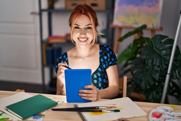 Young caucasian woman artist smiling confident using touchpad at art studio