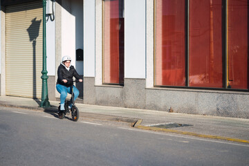 40 year old woman riding her electric scooter through the streets of the city (Concept of electric mobility)