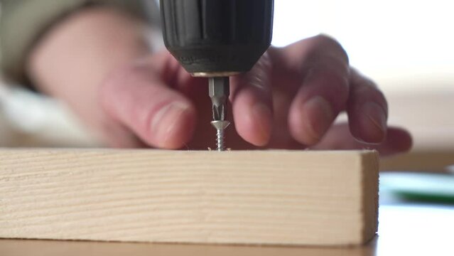 male craftsman screwing a self-tapping screw into a board with a screwdriver. close-up
