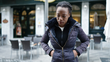 African american woman standing with serious expression at coffee shop terrace