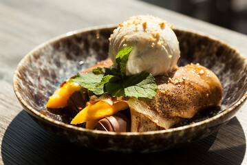 portion of creamy ice cream with mango and mint leaf