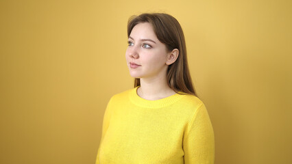 Young blonde woman standing with serious expression over isolated yellow background