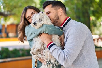 Man and woman kissing dog sitting together at park