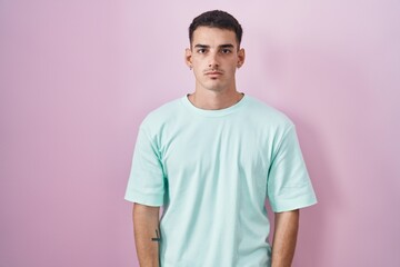 Handsome hispanic man standing over pink background skeptic and nervous, frowning upset because of...