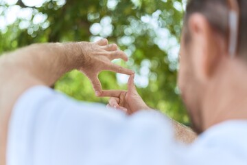 Middle age man doing photo gesture with hands at park