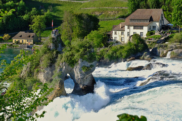 Rocky cliffs stand by the water force of Rhine waterfalls in Neuhausen, Schaffausen, Switzerland....