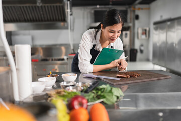 Happy student Asia woman chef quality checking steak at kitchen background 