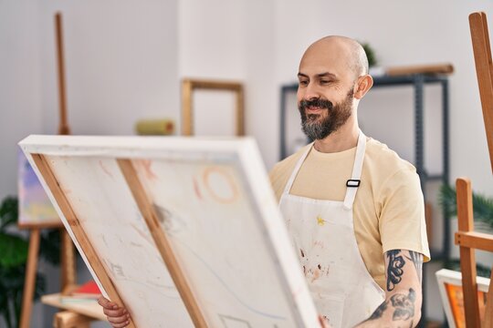 Young bald man artist smiling confident looking draw at art studio