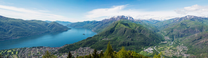 Fototapeta na wymiar Panoramic view of Lake Maggiore and the city of Locarno and Ascona in a sunny day in Summer, turquoise water and clear sky. Photo taken from the mount Cardada in Ticino, Switzerland