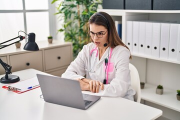 Beautiful doctor woman working on online appointment scared and amazed with open mouth for surprise, disbelief face