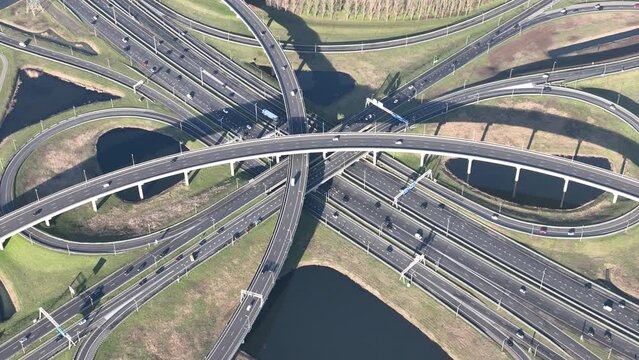 A mesmerizing aerial drone video of a bustling highway multilevel intersection captures the intricate web of roads and vehicles.