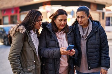 Three woman mother and daughters using smartphone at street