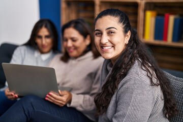 Three woman using laptop sitting on sofa at home