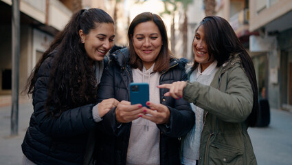 Mother and daugthers using smartphone standing together at street