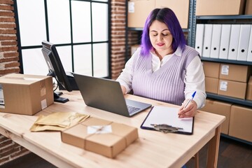 Young beautiful plus size woman ecommerce business worker using computer writing on document at office