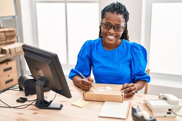 African american woman ecommerce business worker writing on package at office