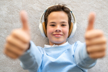 Young man listening to music wearing headphones at homes doing happy thumbs up gesture with hand....