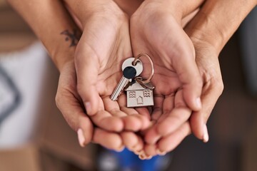 Woman and girl mother and daughter hands holding key at new home