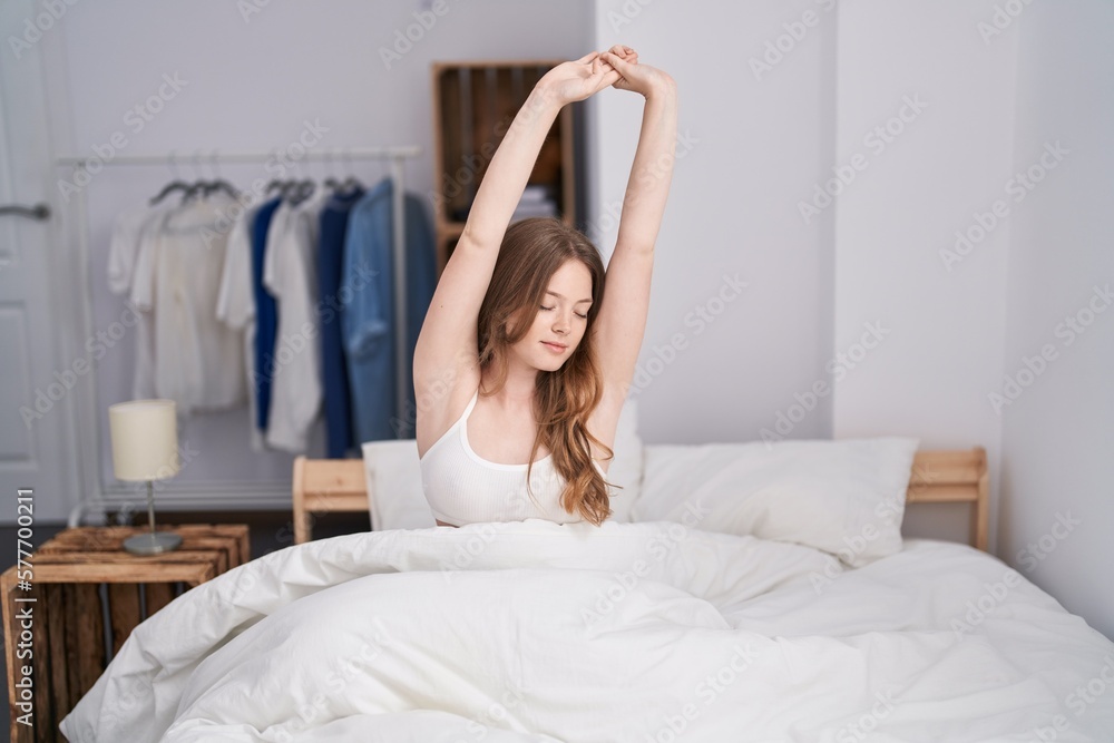 Poster Young woman waking up stretching arms at bedroom