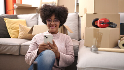 Young african american woman smiling confident using smartphone at new home