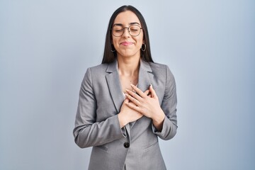 Hispanic business woman wearing glasses smiling with hands on chest with closed eyes and grateful...
