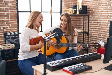 Fototapeta na wymiar Two women musicians singing song playing classical guitar and ukulele at music studio