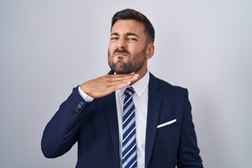 Handsome hispanic man wearing suit and tie cutting throat with hand as knife, threaten aggression with furious violence