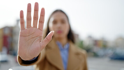 Young beautiful hispanic woman doing stop gesture with hand at street