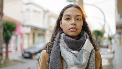 Young beautiful hispanic woman standing with serious expression at street