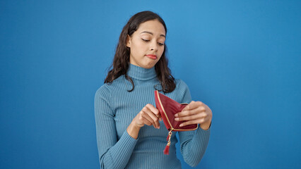 Young beautiful hispanic woman showing empty wallet over isolated blue background