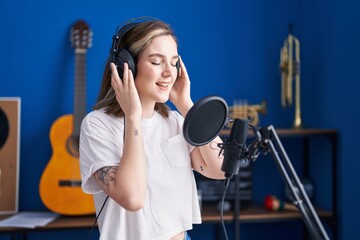 Young woman artist singing song at music studio