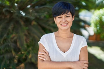 Naklejka premium Middle age chinese woman standing with arms crossed gesture at park