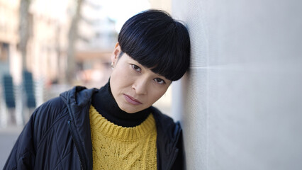 Young chinese woman standing with serious expression at street