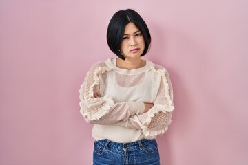 Young asian woman standing over pink background skeptic and nervous, disapproving expression on...