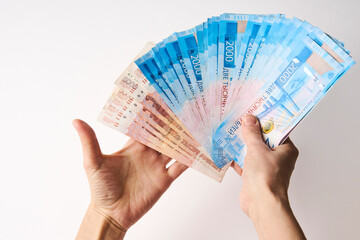 Hands holding Russian money bills, white background, close-up