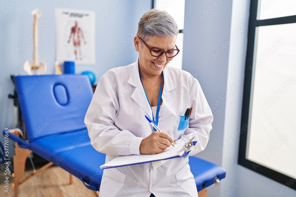 Canvas Prints Middle age woman physiotherapist writing on clipboard at rehab clinic