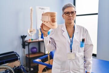 Middle age woman holding cervical neck collar looking positive and happy standing and smiling with a confident smile showing teeth